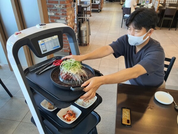 사진은 한우프라자의 고객이 서빙로봇을 통해 주문한 음식을 받고 있다
