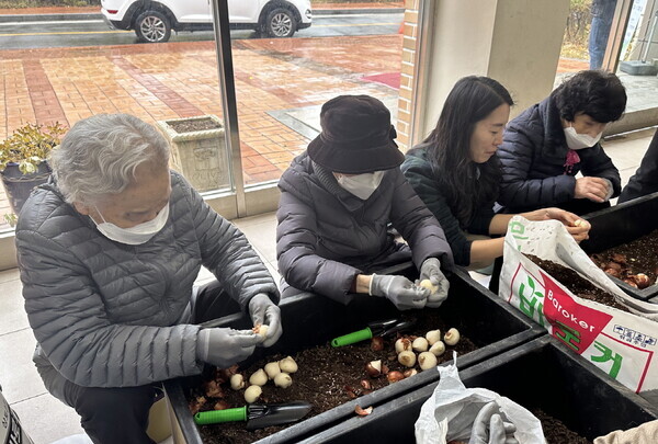 27일 경기도 부천 공공임대아파트(범박 휴먼시아 1단지)에서 진행된 ‘생활숲 사회통합형 산림복지서비스 시범사업’의 참여자들이 단지에 설치될 대형 화분에 구근심기 활동을 하고 있다.(한국산림복지진흥원 제공)