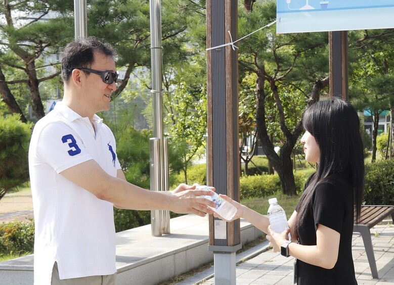 축산물품질평가원 직원이 지역주민에게 얼음 생수를 나누어주고 있다.